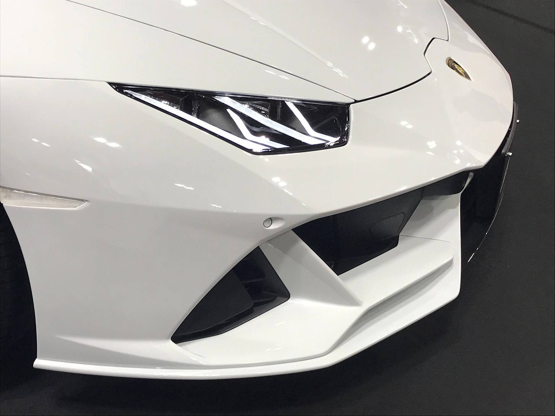 A luxury sports car in the process of receiving a custom body kit installation, highlighting precise craftsmanship and geometric design elements.