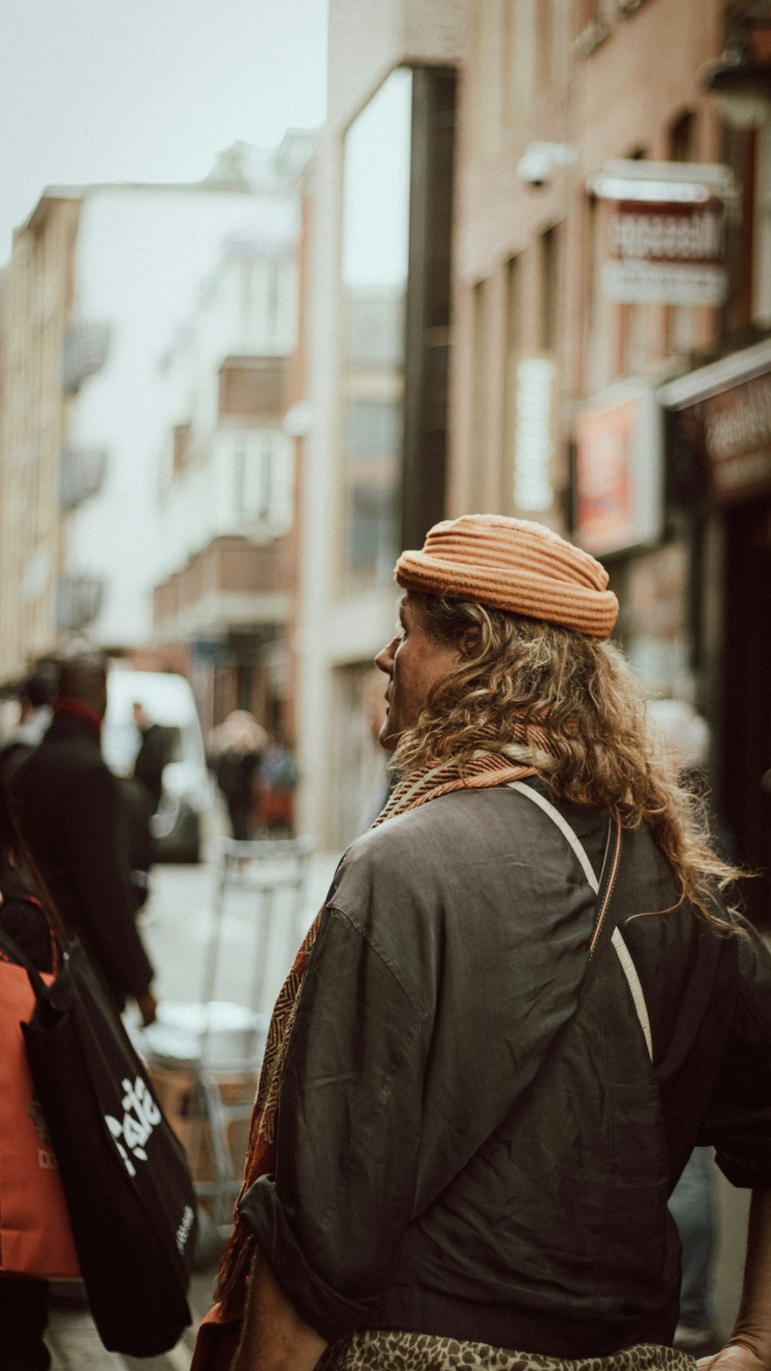 woman in black coat and brown knit cap walking on street during daytime