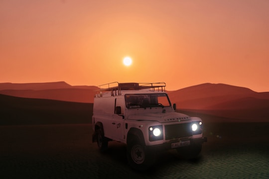 a white truck driving through a desert at sunset