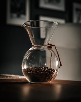 Barista preparing a pour-over coffee with steam rising, framed by subtle clay and soft gold accents.