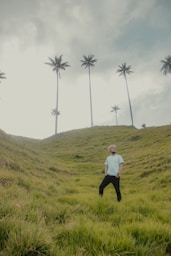 woman in white long sleeve shirt and black pants standing on green grass field during daytime