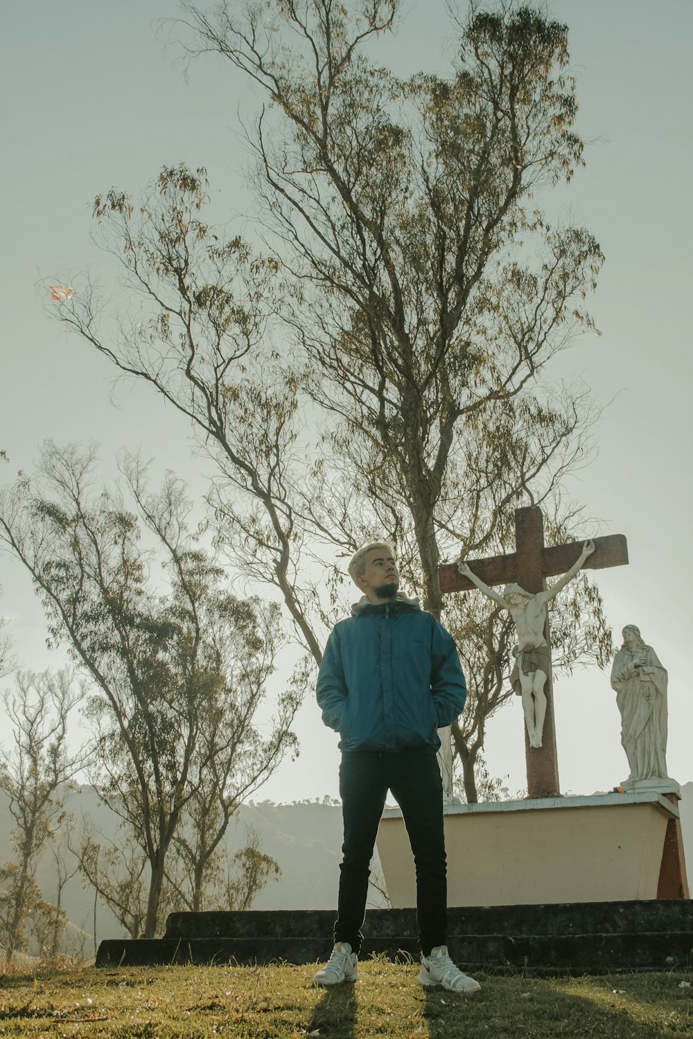 Una persona parada frente a una cruz