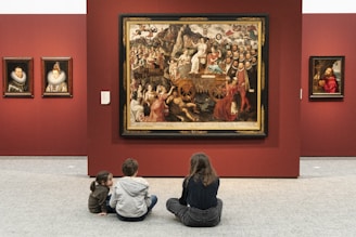 kid in black jacket sitting on floor with kids sitting on floor painting