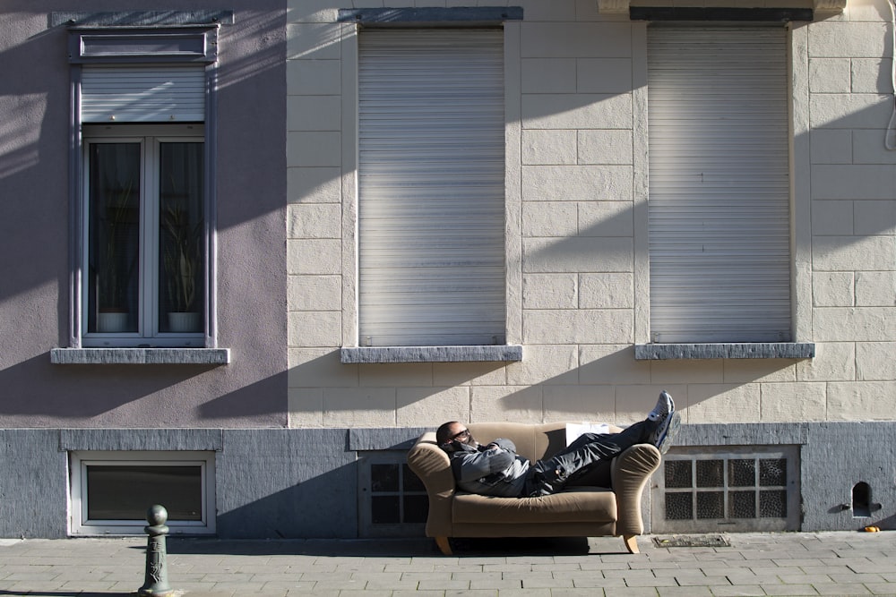 man in black jacket lying on brown brick floor