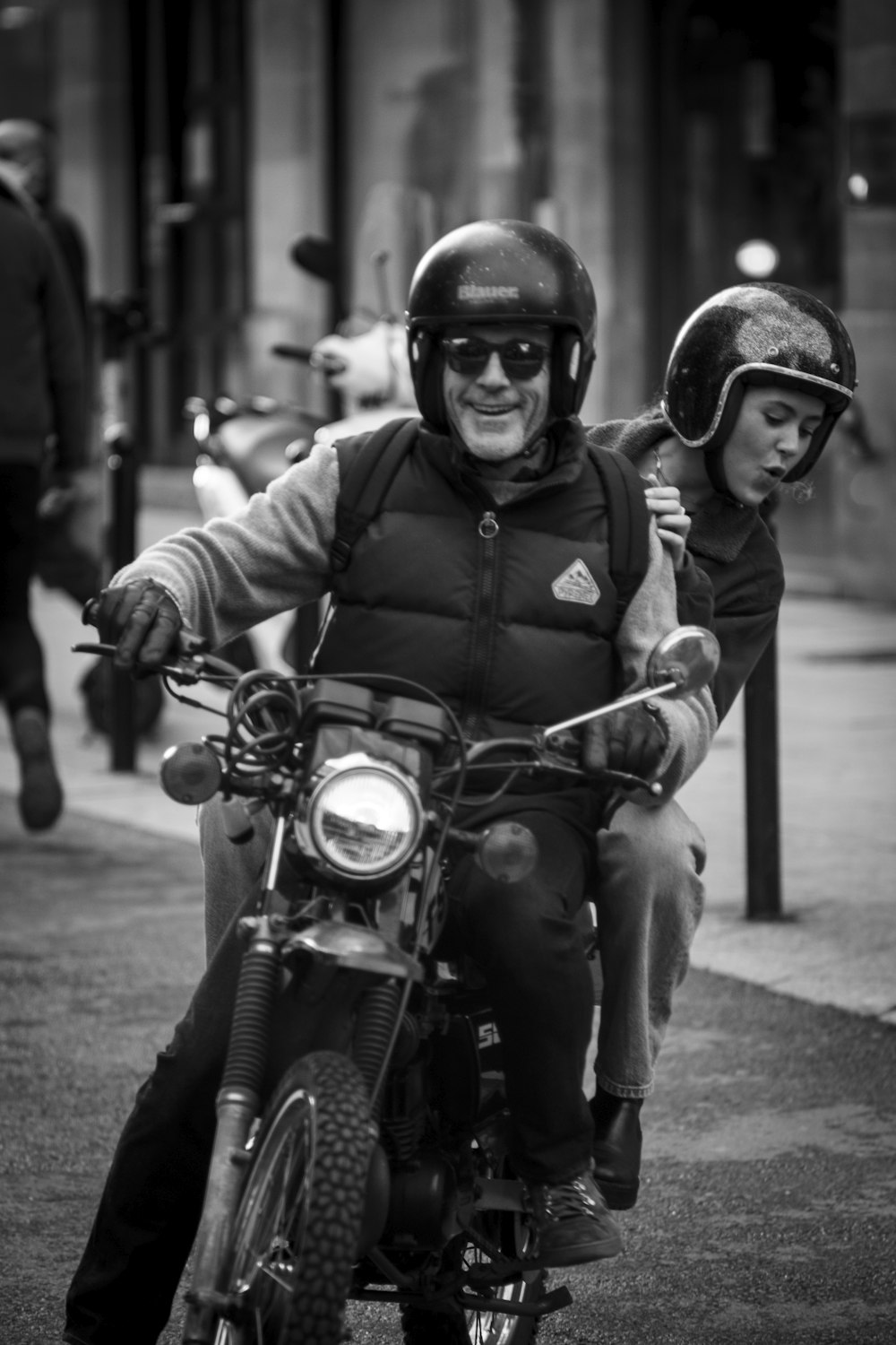 a man riding on the back of a motorcycle down a street