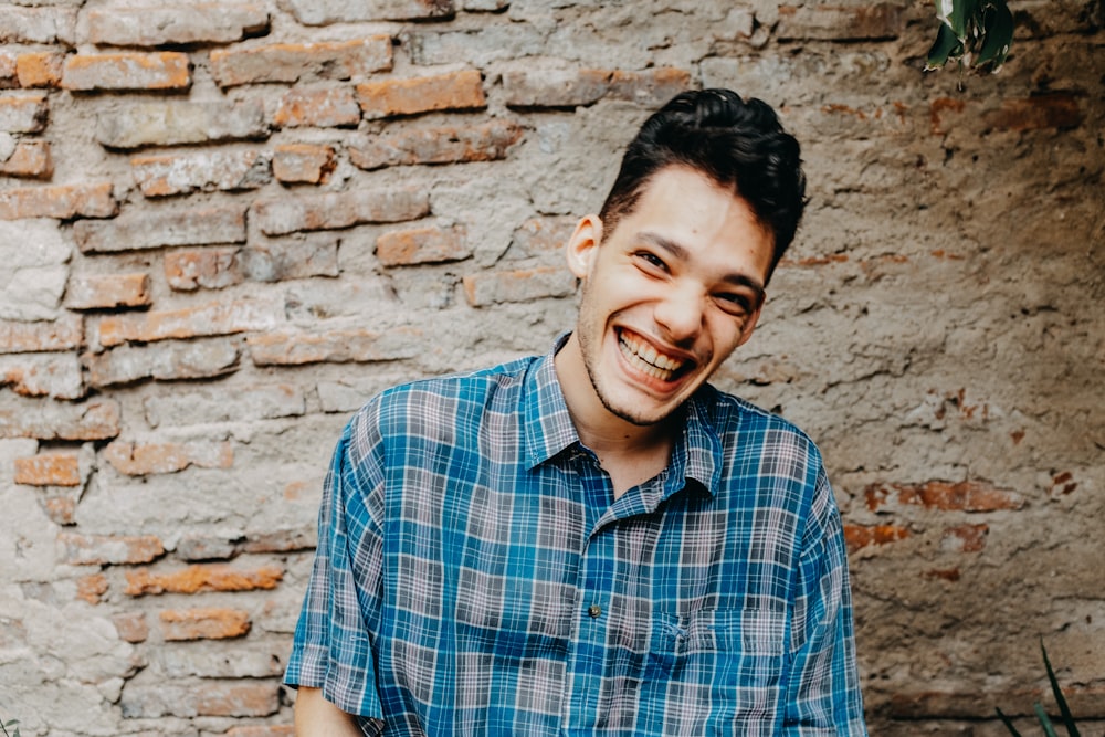 homme en chemise boutonnée à carreaux bleus, blancs et noirs, souriant