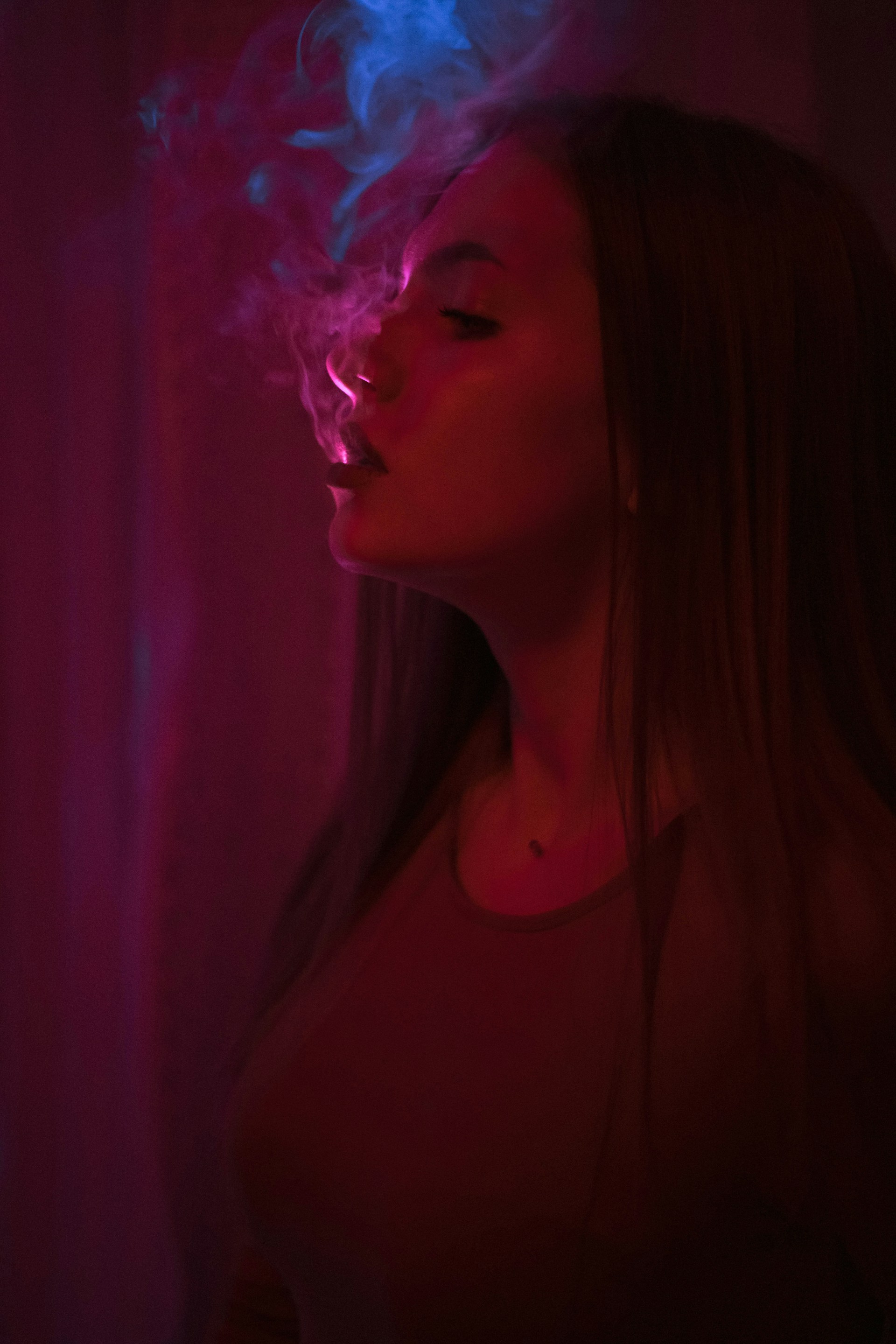 woman in white crew neck shirt with purple smoke in her face