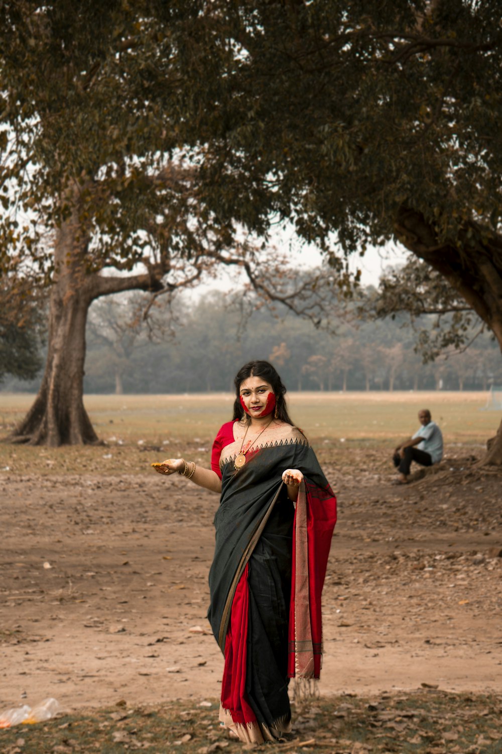 a woman in a red and black sari holding a bottle