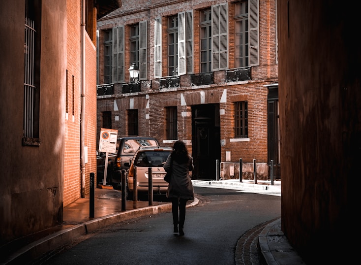 man in black jacket walking on sidewalk during daytime
