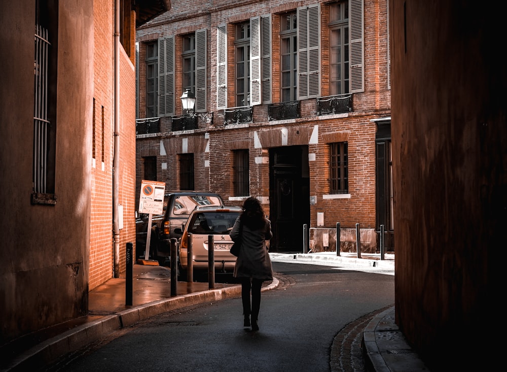 man in black jacket walking on sidewalk during daytime