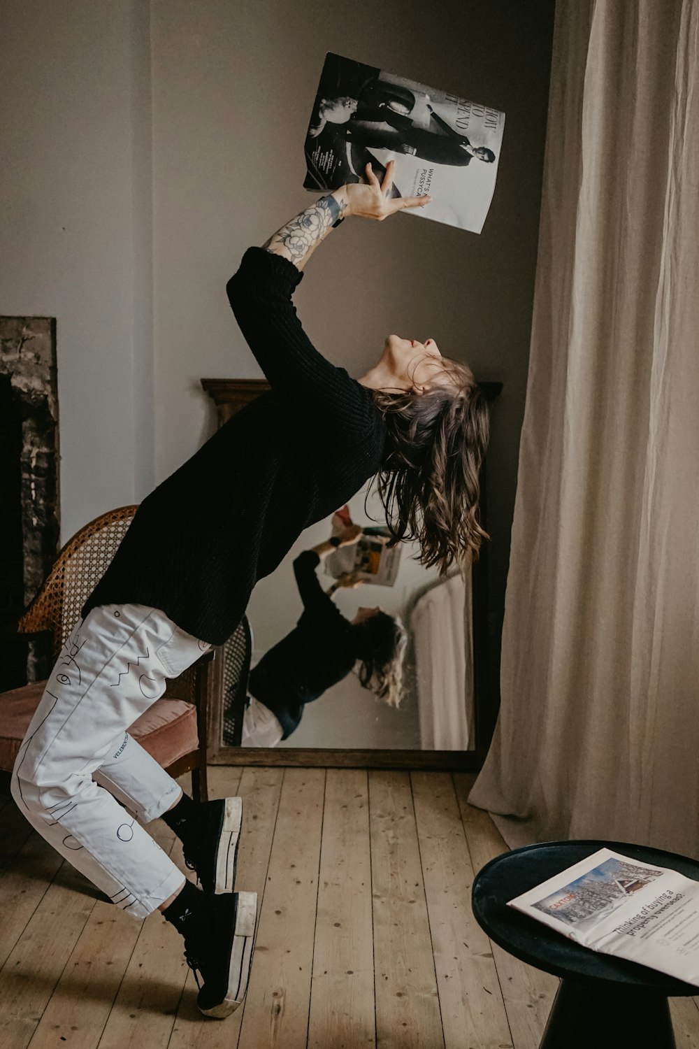 woman in black long sleeve shirt and white pants sitting on brown wooden chair