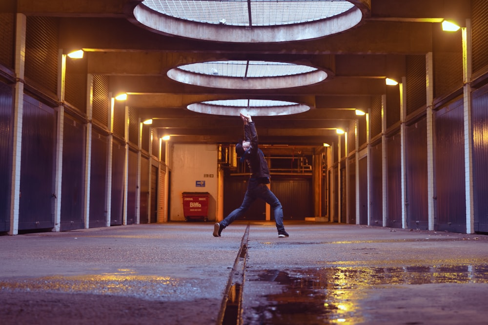 woman in black jacket and blue denim jeans jumping on brown wooden skateboard