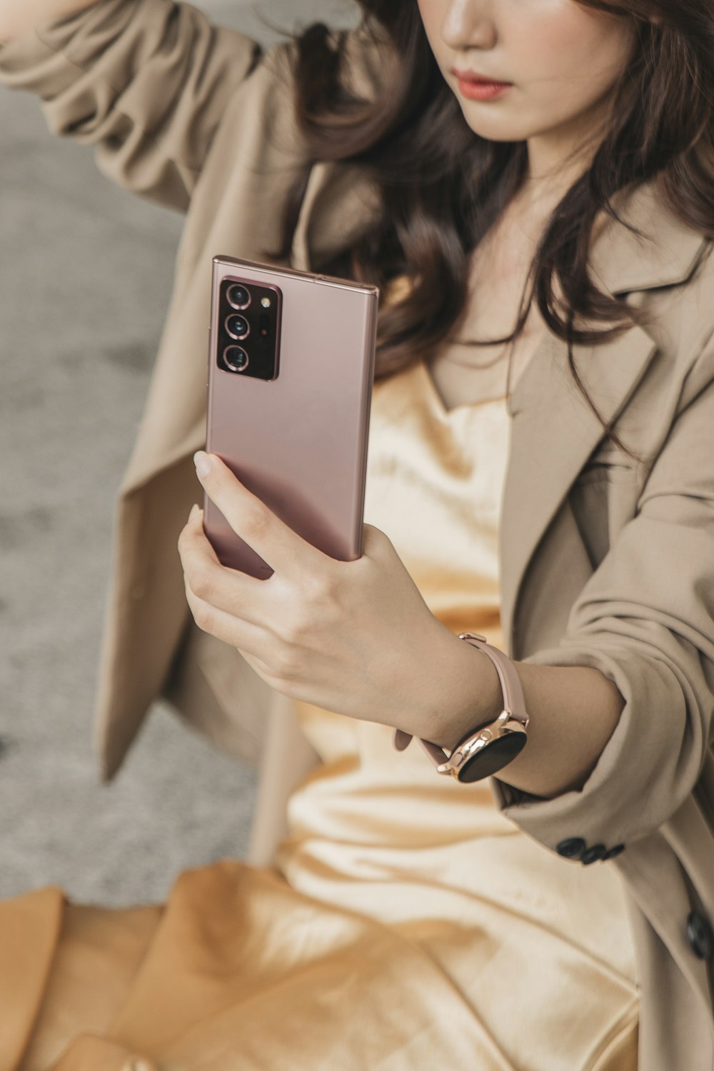 woman in beige blazer holding white smartphone