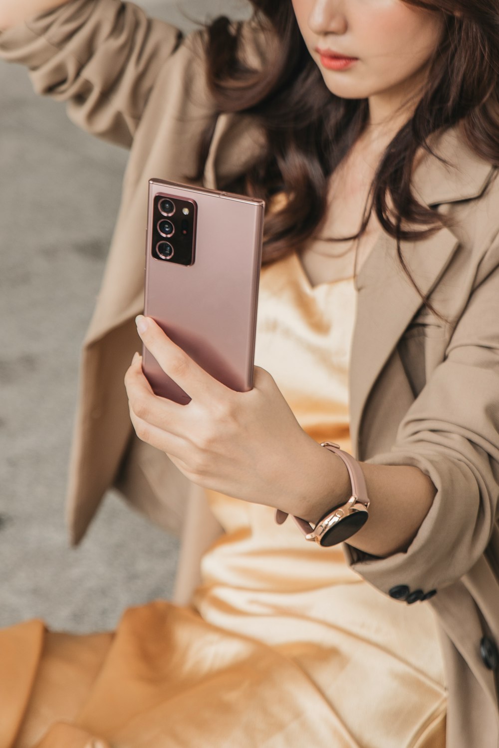 woman in beige blazer holding white smartphone