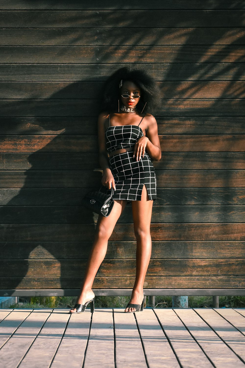 woman in black and white plaid tube dress standing beside brown wooden wall