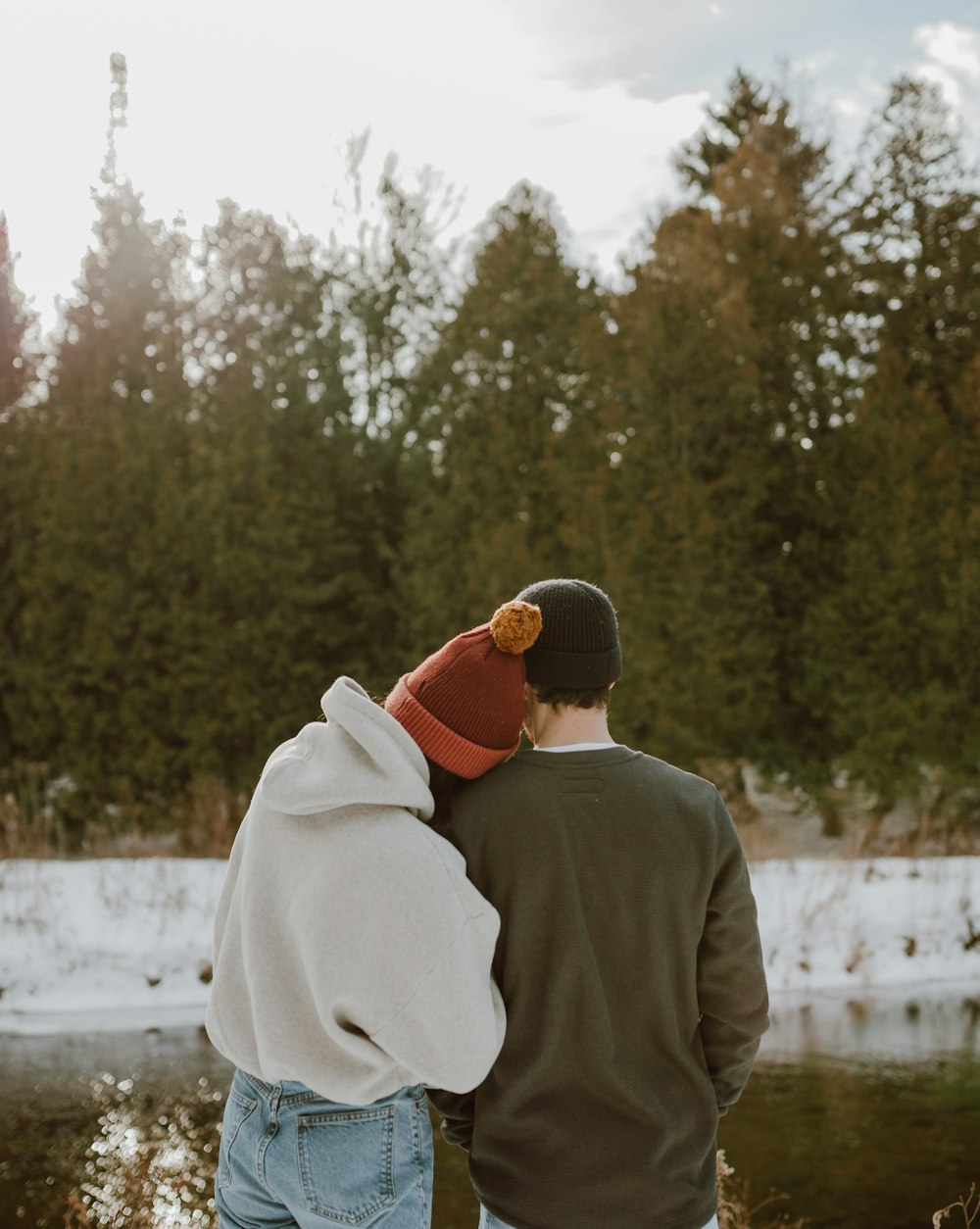 Homme en manteau blanc et bonnet en tricot rouge debout sur un sol enneigé pendant la journée