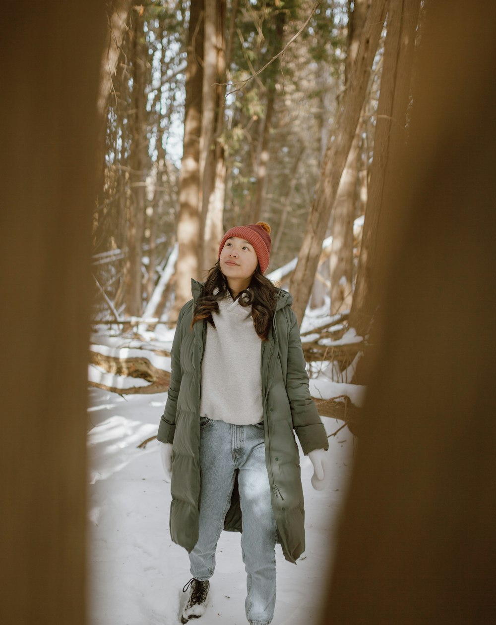 woman in gray coat standing on snow covered ground during daytime