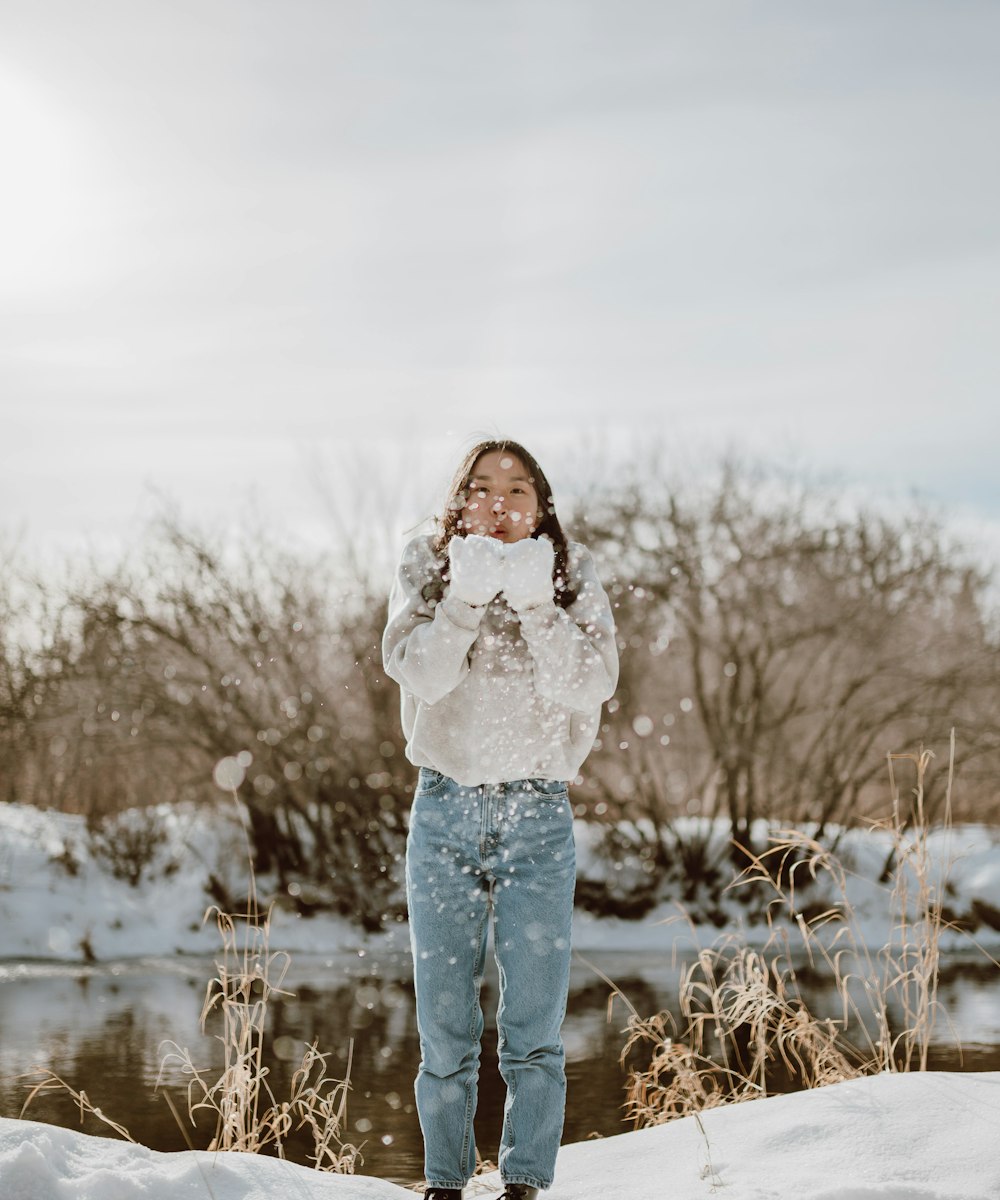 woman in white long sleeve shirt and blue denim jeans standing on brown grass field during