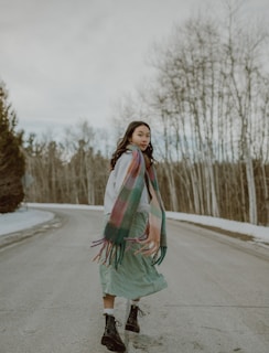 A model wearing a stylish knitted scarf while walking in a vibrant autumn park.