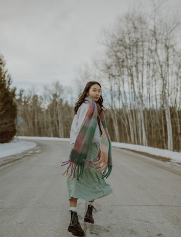 A model wearing a stylish knitted scarf while walking in a vibrant autumn park.