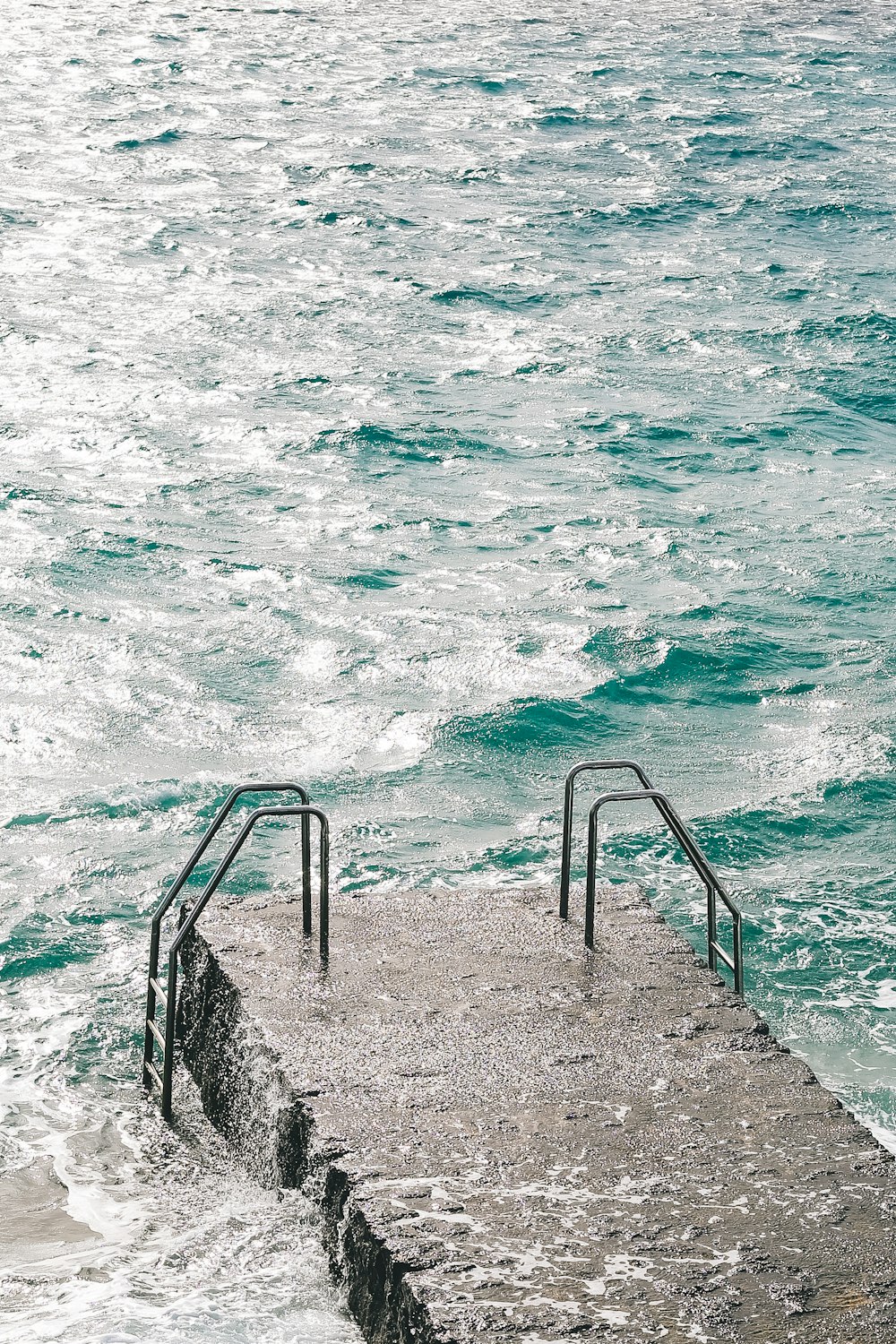 gray concrete stairs beside body of water during daytime