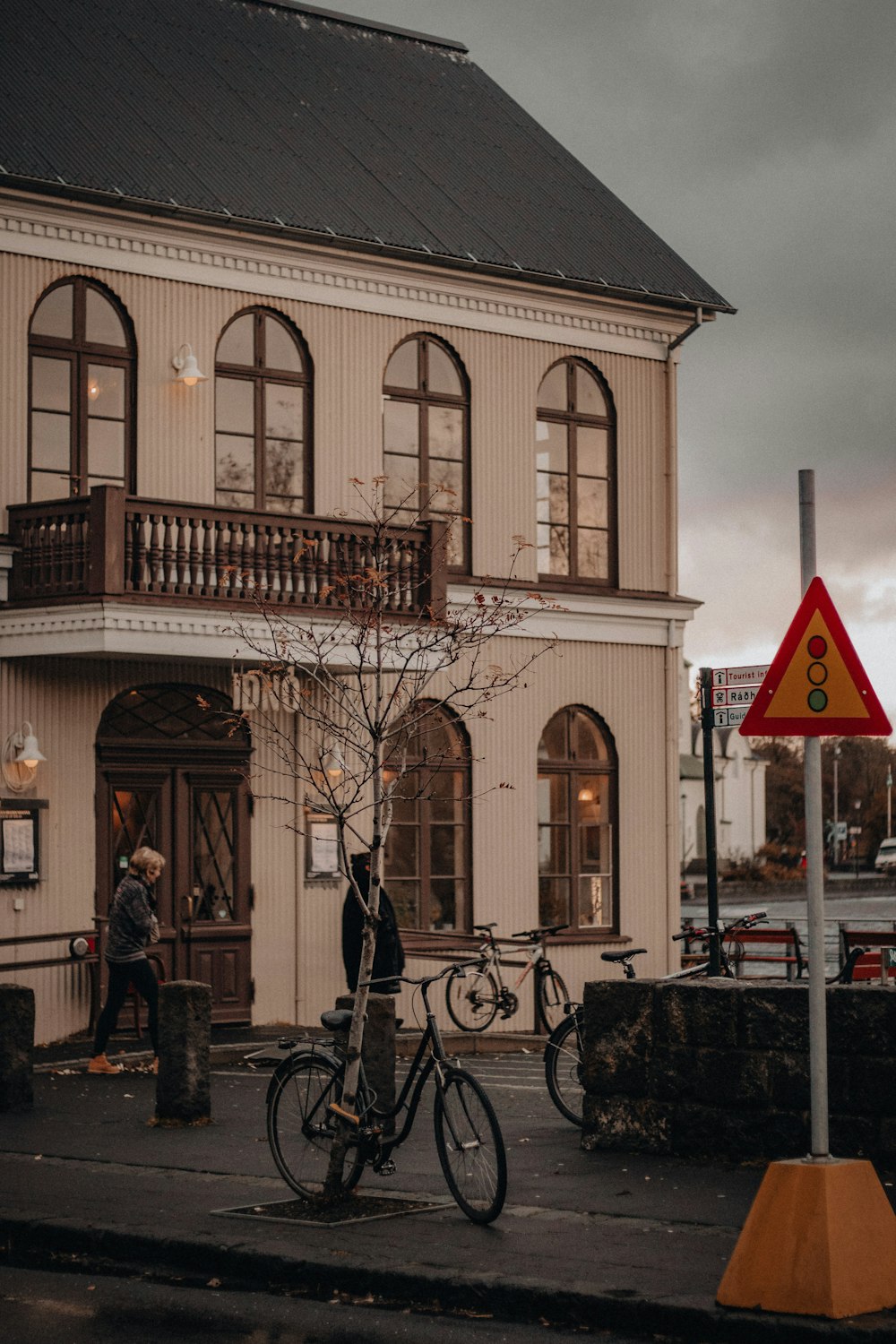 man in black jacket and black pants standing beside bicycle near brown concrete building during daytime