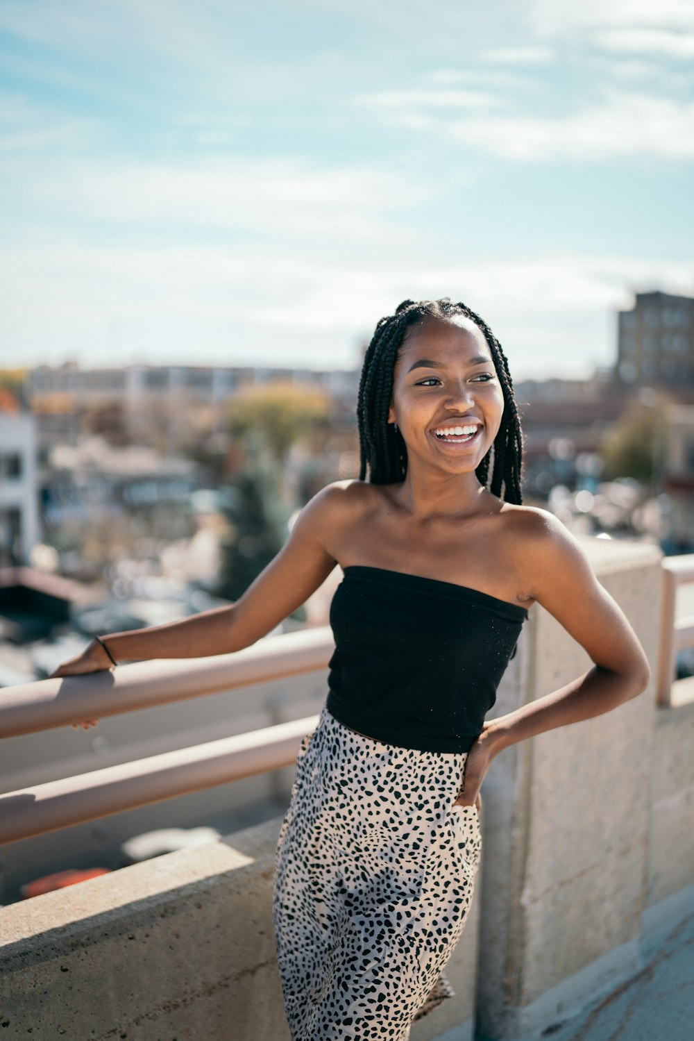 woman in black tube top and white and black leopard print skirt standing on bridge during