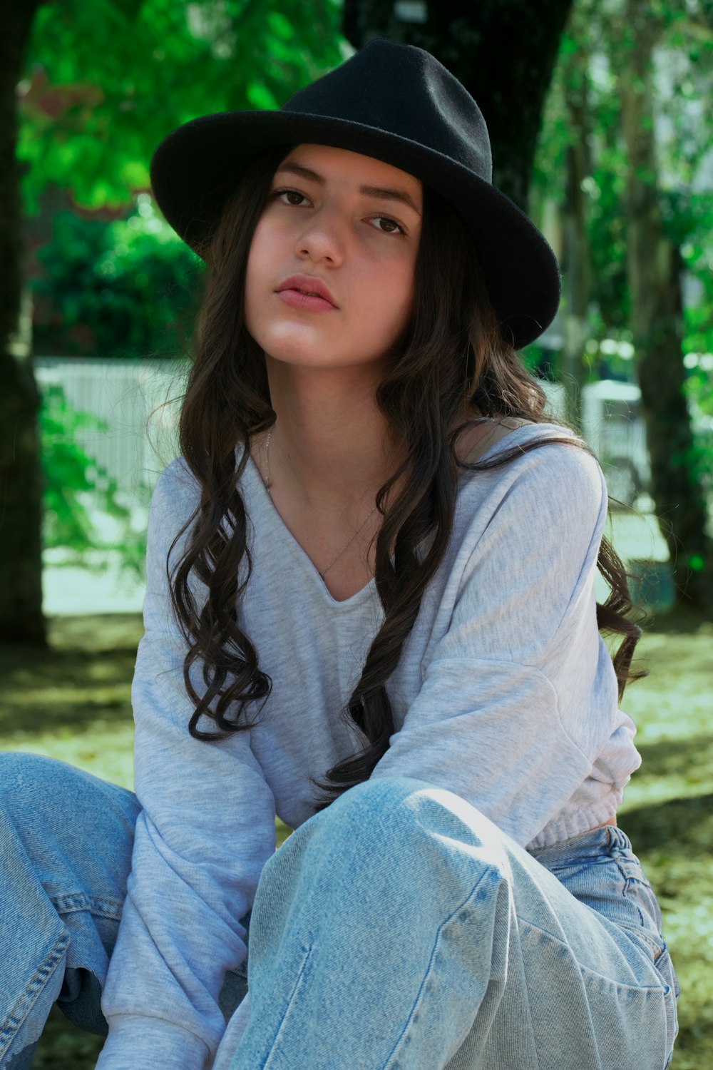 Una niña con un sombrero negro sentada en el suelo