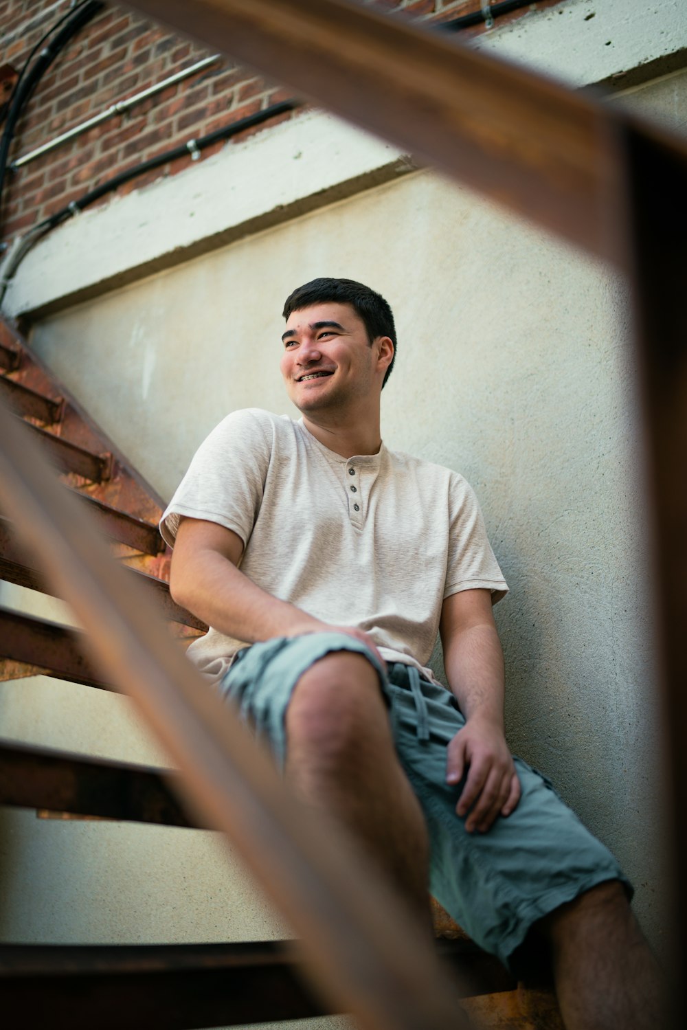 man in white crew neck t-shirt and blue denim jeans sitting on brown wooden stairs