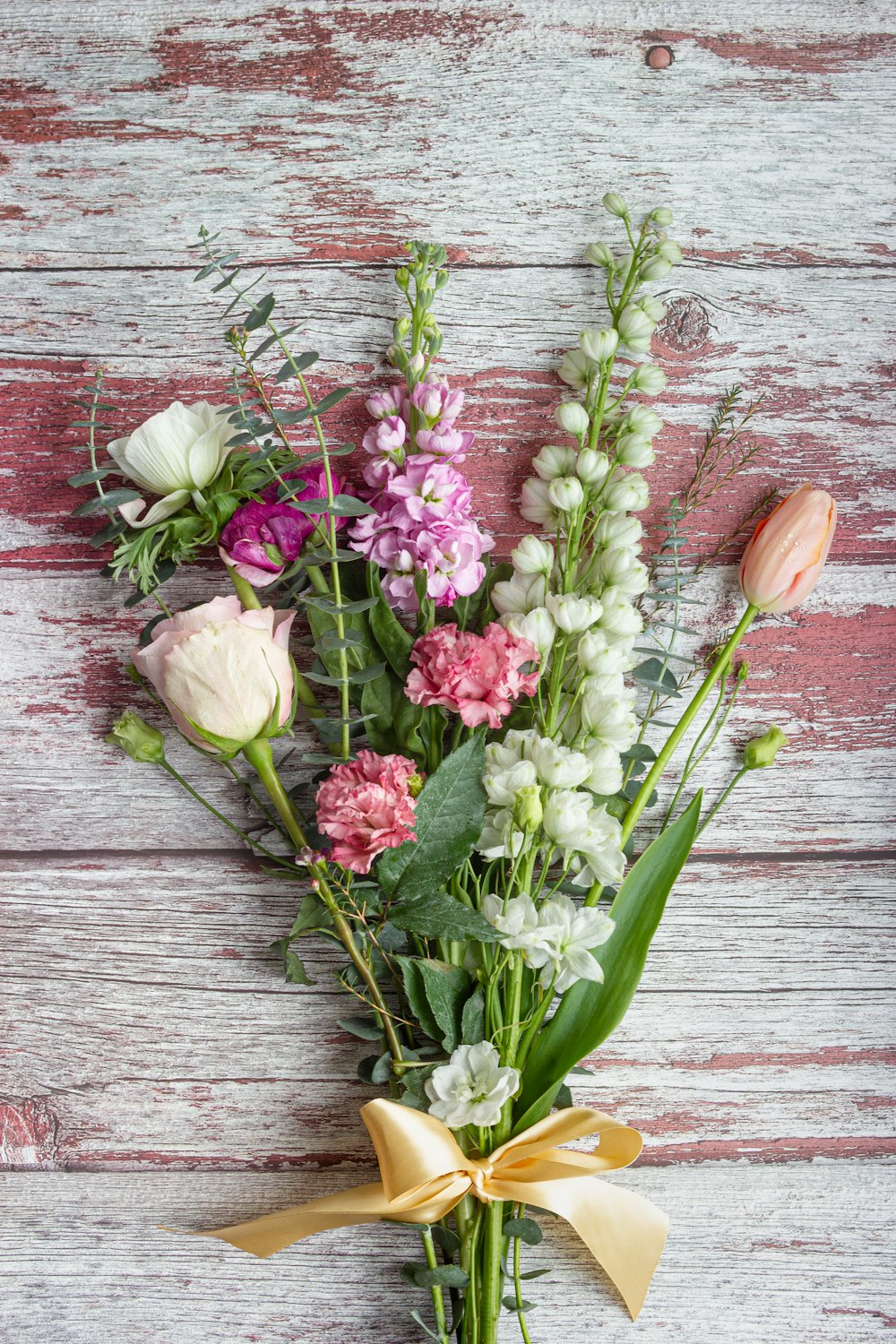 pink and white tulips on brown wooden surface