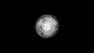A circular, translucent object with multiple concentric rings is centered against a completely black background. The object resembles a cross-section of a geological formation or ice, with varying shades of white and gray.