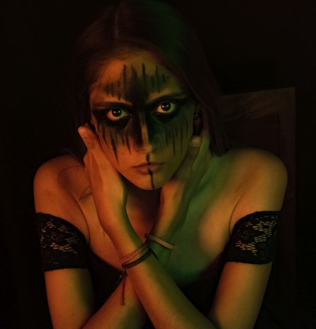 A creative portrait featuring colorful face paint and dramatic lighting.
