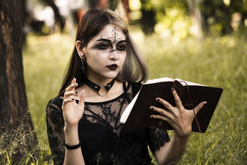 a woman with makeup on holding a book