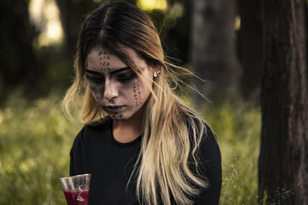 a woman with face paint holding a drink