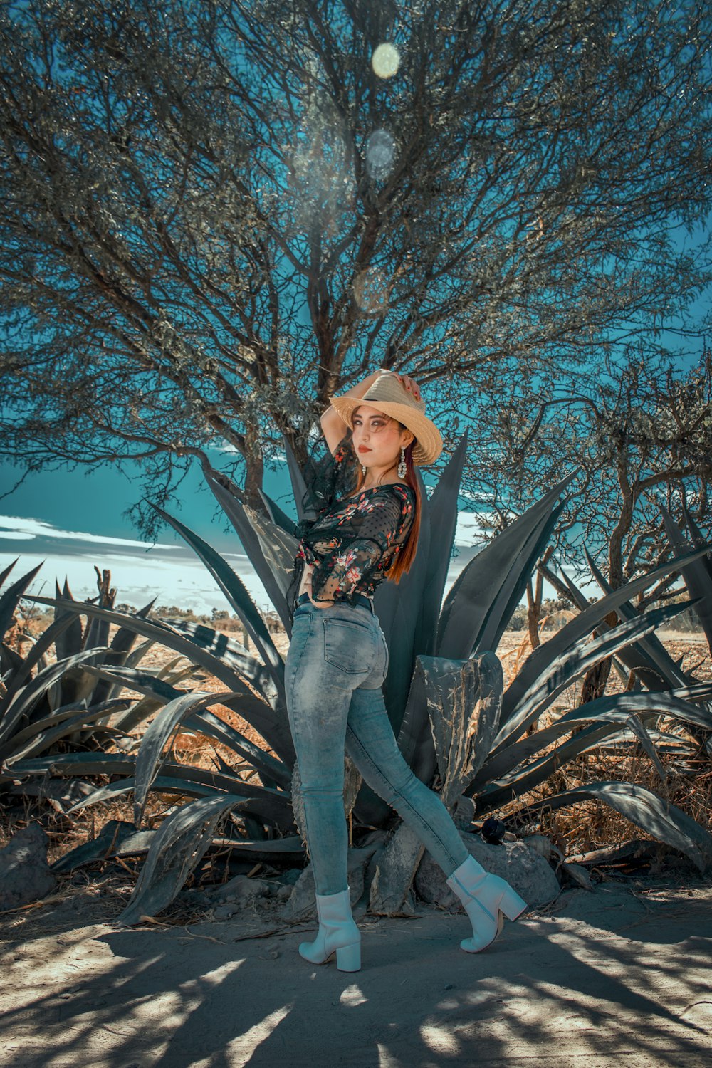 woman in black and brown floral long sleeve shirt and gray pants sitting on brown tree