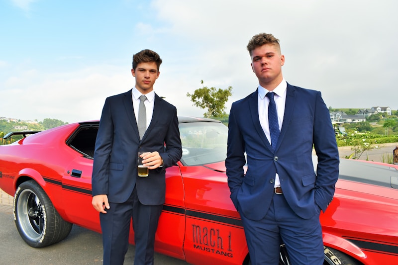 Suited gay men by red car