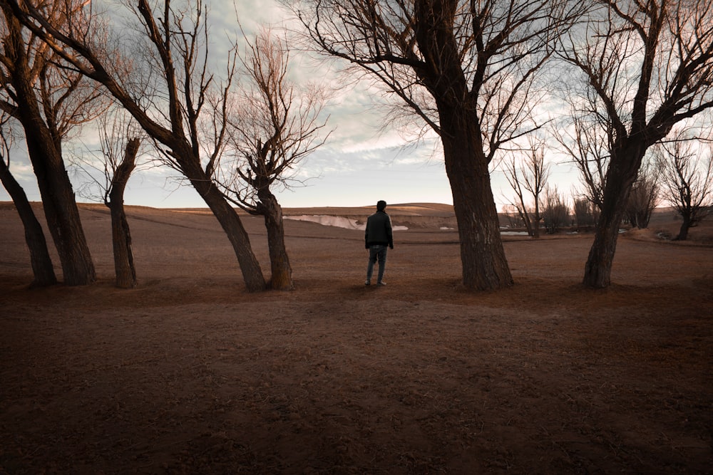 man in black jacket standing on brown field during daytime