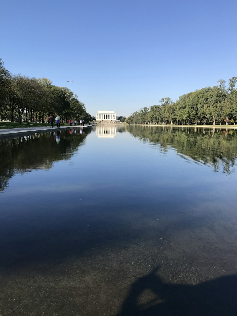 Weißes Betongebäude in der Nähe von grünen Bäumen und See tagsüber