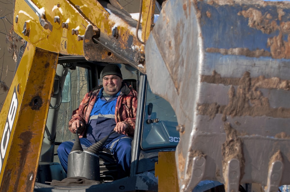 woman in black jacket and blue denim jeans riding on blue and black heavy equipment