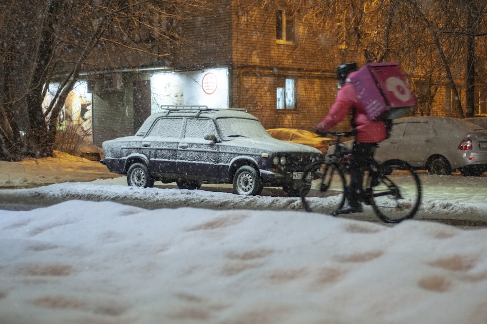 a person riding a bike down a snow covered street