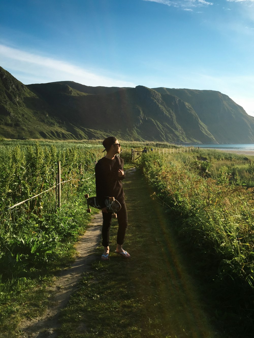 man in black t-shirt and blue denim jeans walking on pathway during daytime