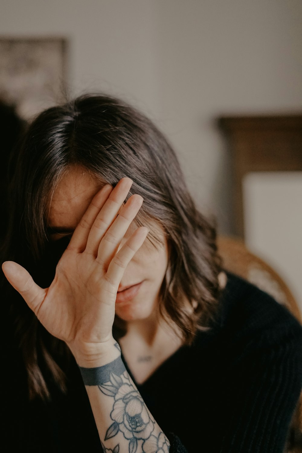 woman in black blazer covering her face