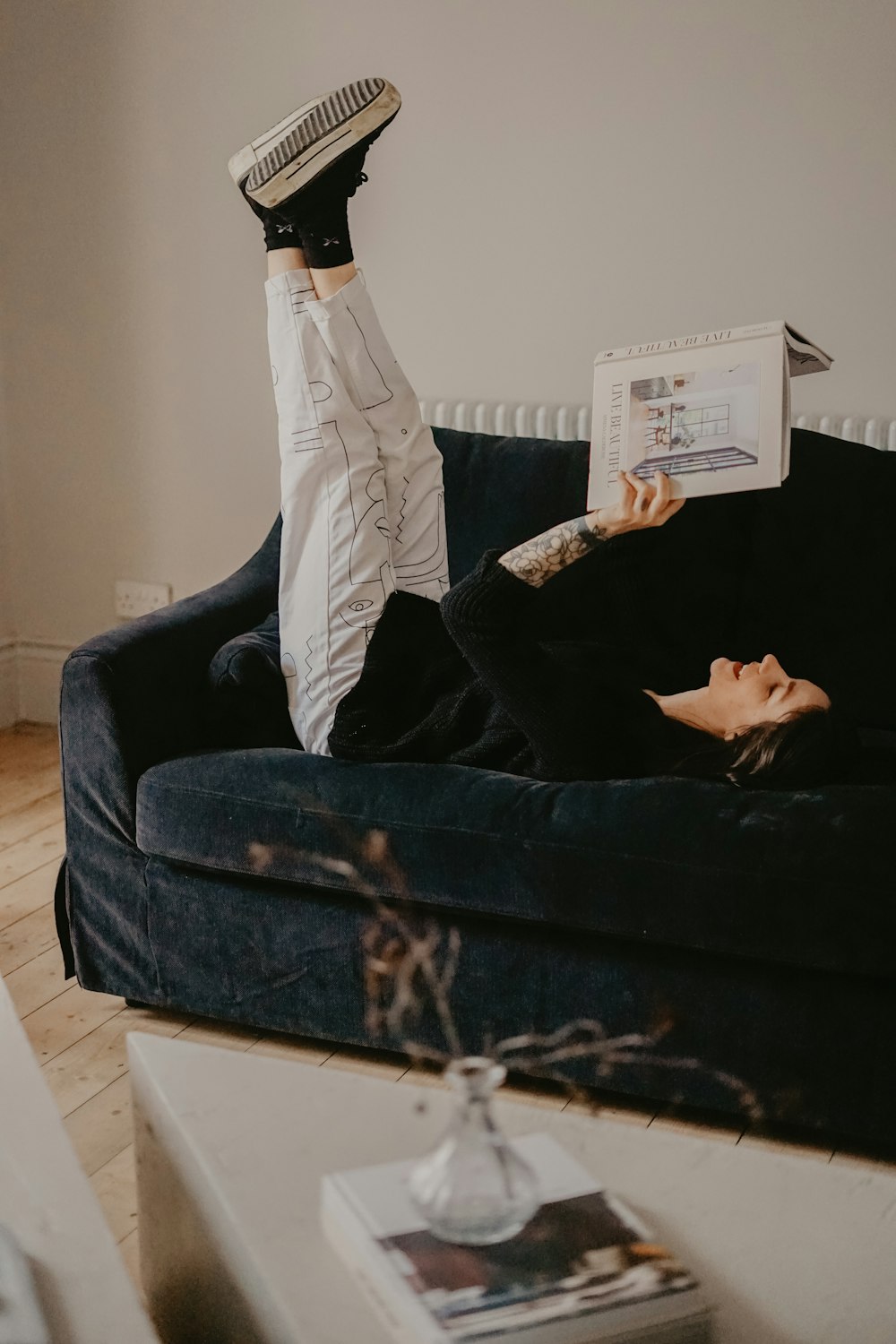 man in white pants lying on black couch