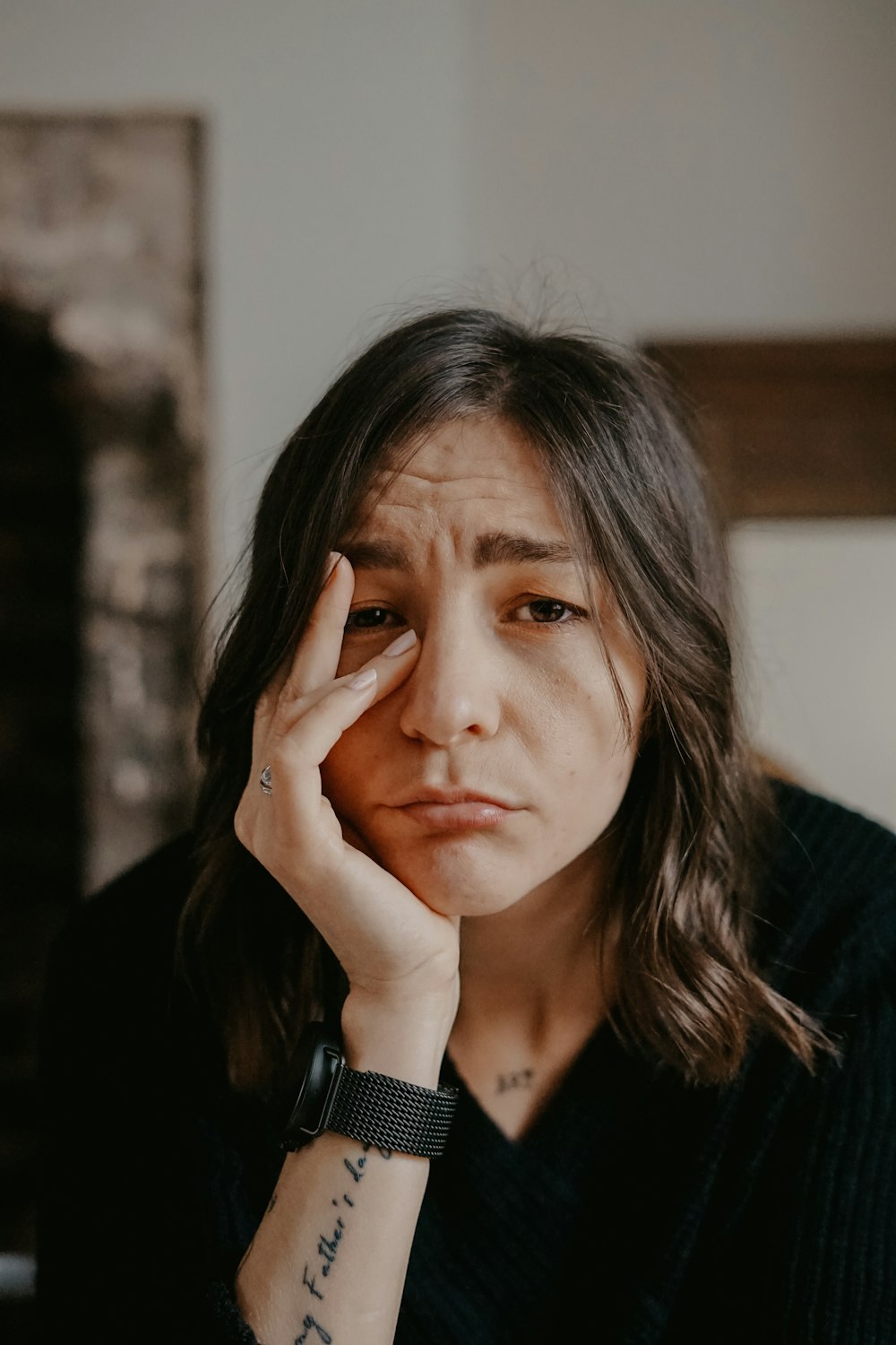 woman in black blazer covering her face