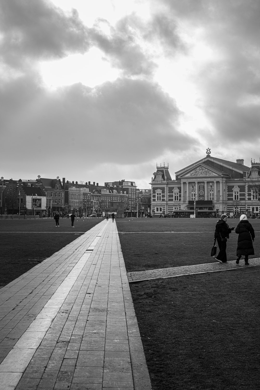 grayscale photo of people walking on sidewalk near building