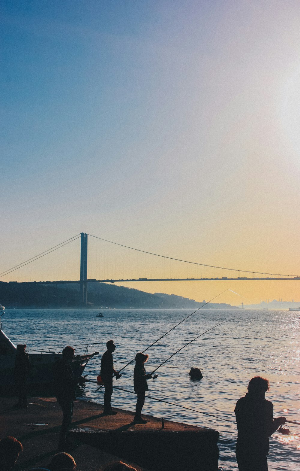 silhouette of people sitting on bench near body of water during daytime