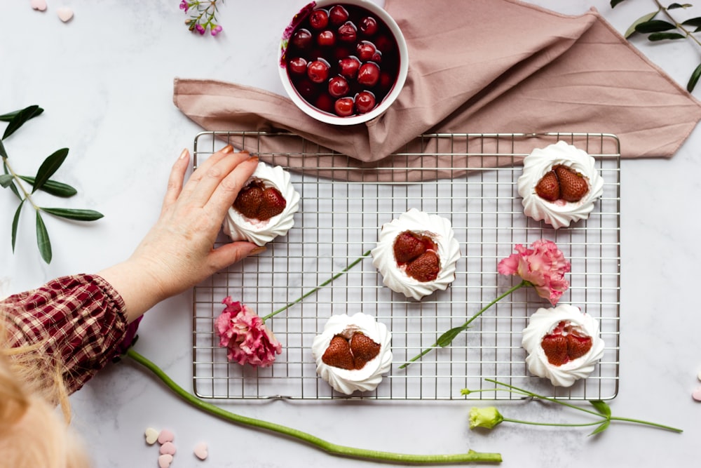 person holding white ceramic plate with red and white flowers