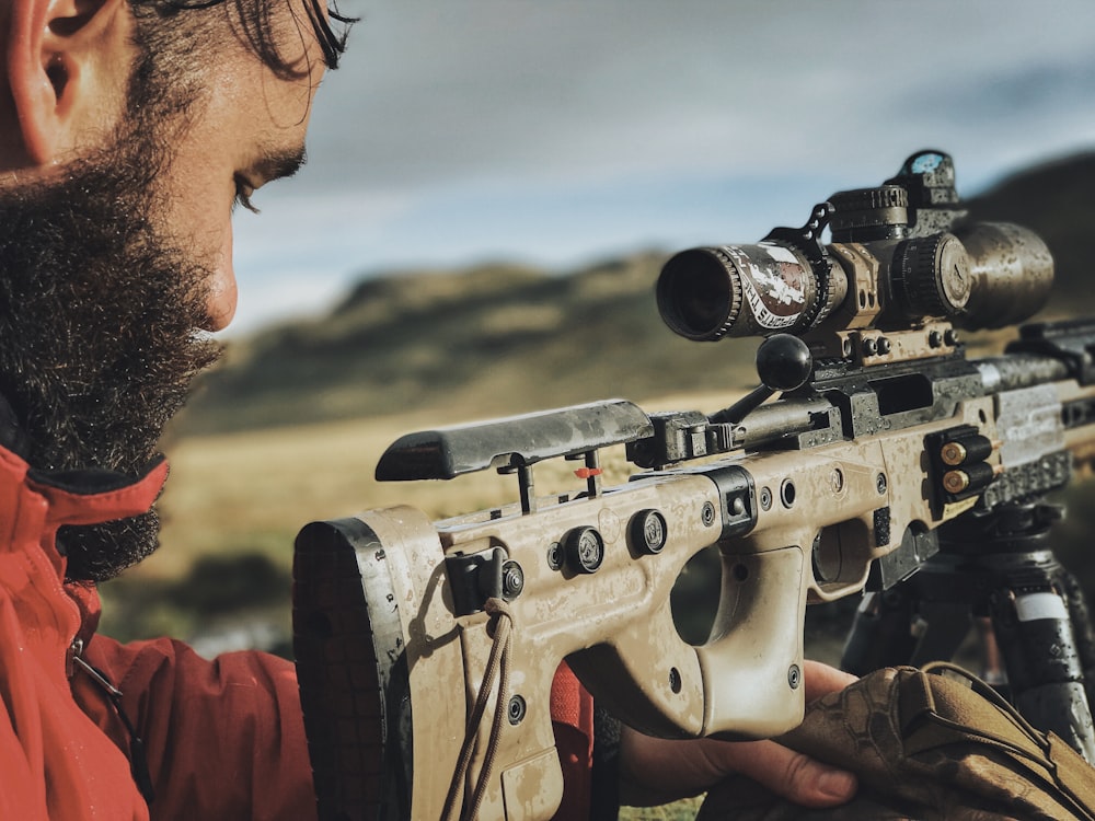 homem na camisa vermelha segurando rifle preto