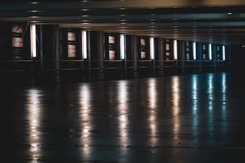 A sleek, ultra-wide shot of a high-tech industrial space softly lit by rows of elegant LED lights under a lofty steel ceiling.