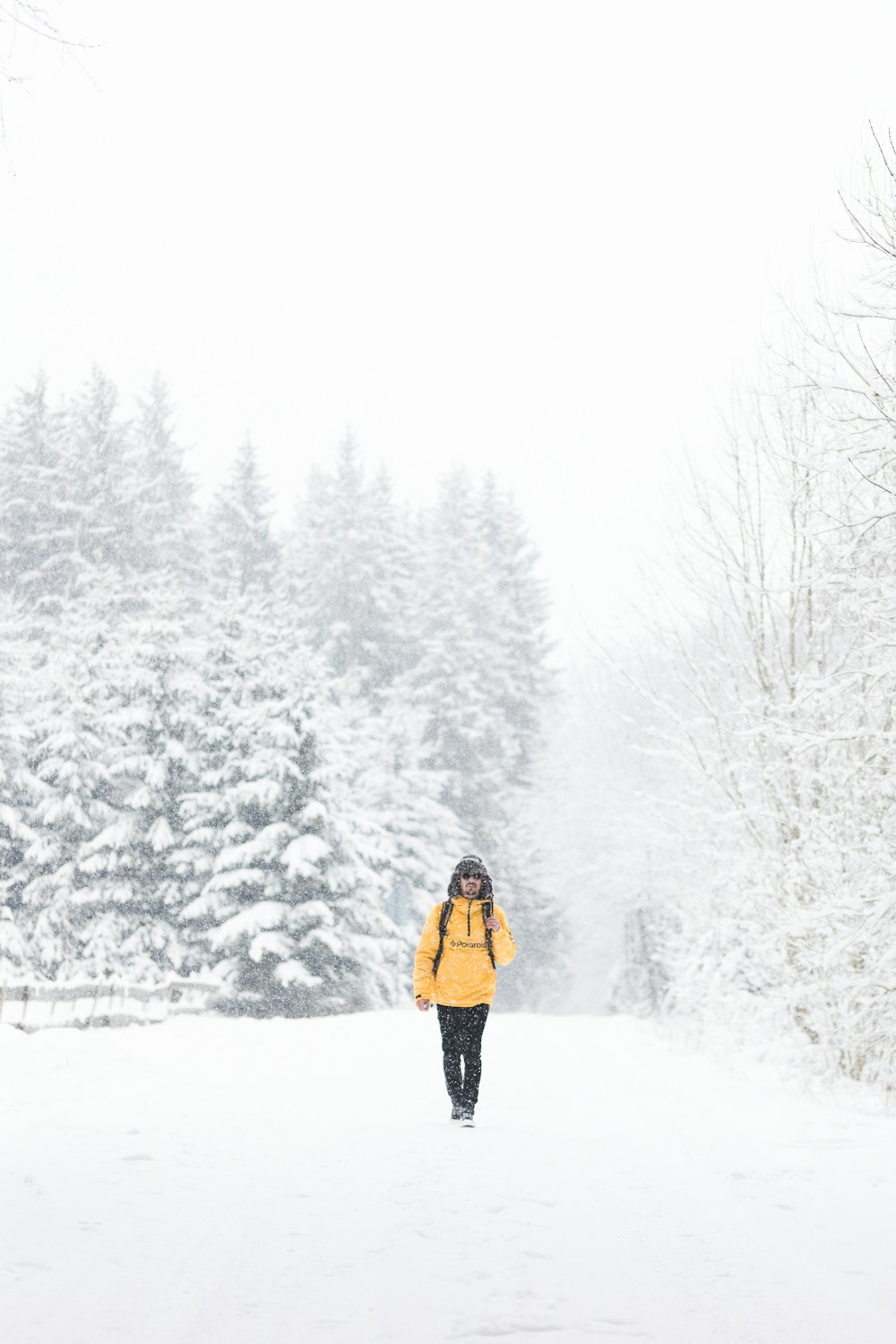 Frau in gelber Jacke und schwarzer Hose, die tagsüber auf schneebedecktem Boden steht